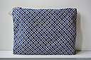 Grande trousse plate en popeline de coton aux motifs géométriques bleu, beige et rouge. Fermeture éclair métallique noir. Entièrement doublée en coton bleu marine